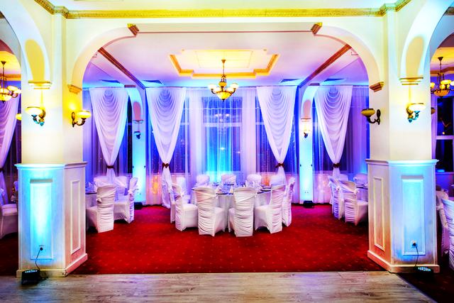 Draperii albe luminate în violet în spatele meselor